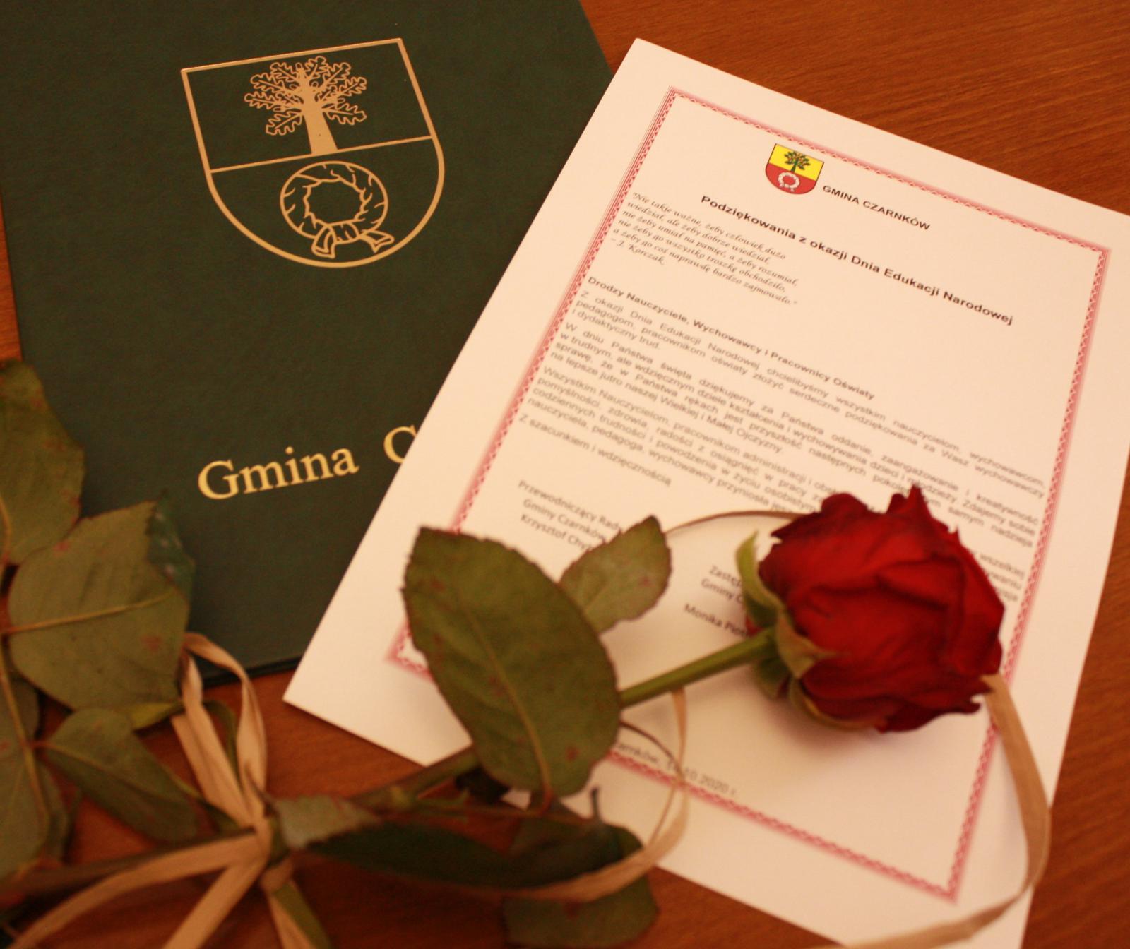 Zdjęcie przedsatwiające okłądkę dyplomu, dyplom i czerwoną różę